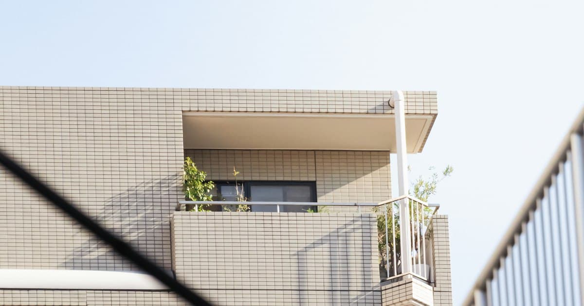 植栽のあるバルコニーが並ぶ白い外観の集合住宅